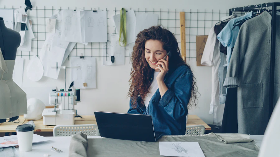 Empreendedora de moda sorrindo ao telefone no ateliê